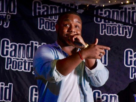 Lance Greenwood passionately reciting poetry on stage.